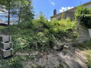 Failing block retaining wall with crumbling structure and exposed soil before reconstruction in Mt. Airy Ohio
